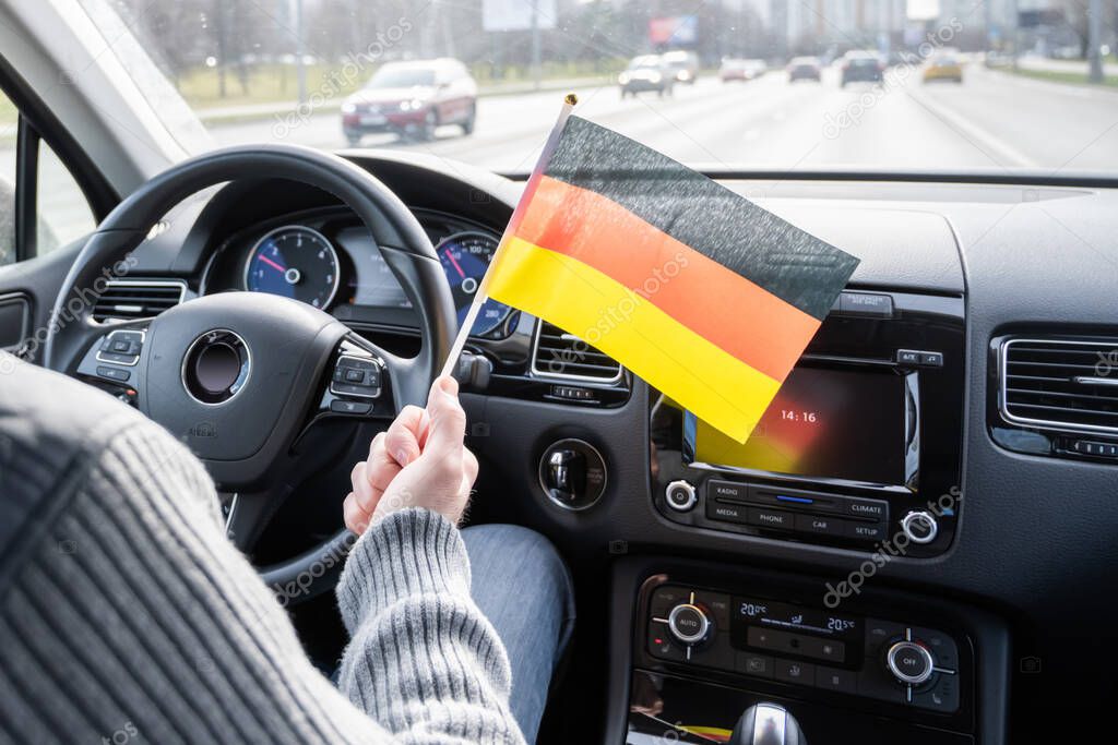 Middle aged man with Germany, flag driving a car.  Europe.