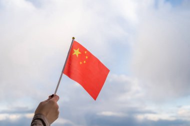 Gün batımında sallanan Çin bayrağı taşıyan kadın eli. Kavram