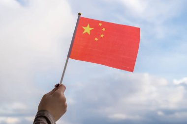 Gün batımında sallanan Çin bayrağı taşıyan kadın eli. Kavram