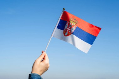 Mavi gökyüzünde sallanan Sırp bayrağıyla bir kadın eli. Sırbistan. Kavram