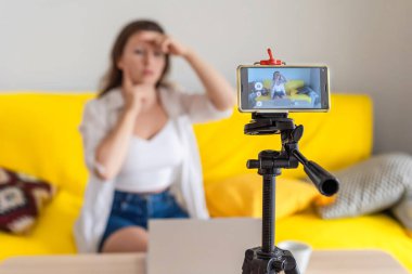 Vlog. Özel ders. Yüz geliştirme. Genç bayan blogcu telefon ekranında resim ya da video çekiyor. Akıllı fonla. Yüz jimnastiği. Cilt gerdirme ve yaşlanma önleyici yüz egzersizleri