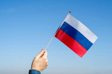Mavi gökyüzünde Rus bayrağı sallayan kadın eli. - Rusya. Kavram