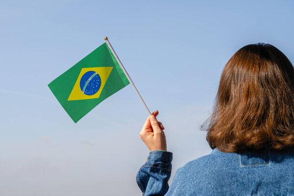Женская рука с бразильским флагом на голубом небе. Южная Америка. Концепция

