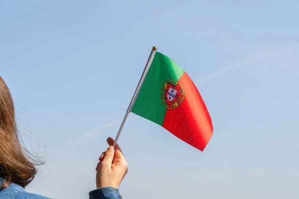 Woman hand with Portuguese swaying flag on the blue sky. Portugal. Concept