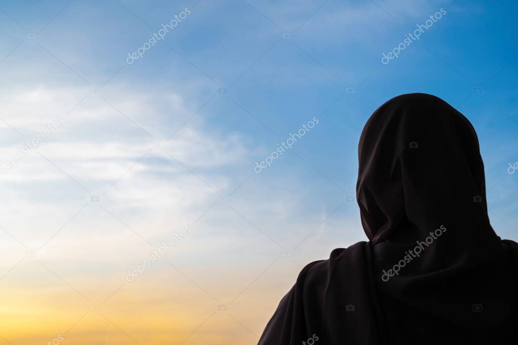 Silhouette of muslim woman in scarf at sunset. America. Concept