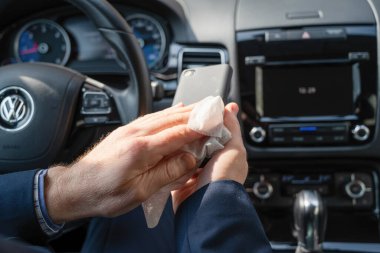 Mavi takım elbiseli orta yaşlı işadamı kendini bakteri ve virüsten korumak için antivirüs antibakteriyel ıslak mendil (peçete) kullanıyor.. 