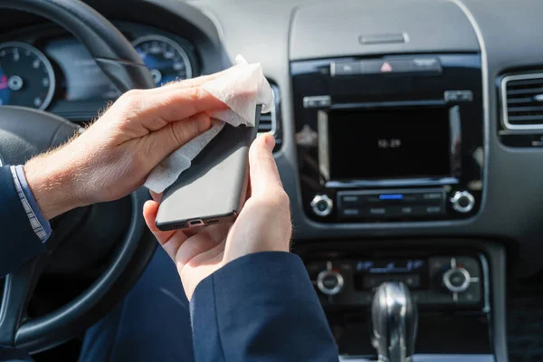 細菌やウイルスから身を守るために アンチウイルス抗菌ウェットワイプ ナプキン を使用して車の中で青いスーツクリーニング携帯電話やガジェットで中世のビジネスマン — ストック写真