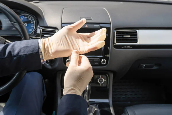 青いスーツの中世のビジネスマンは車を運転している間細菌及びウイルスから身を守るためのゴム手袋を置く コロナウイルス パンデミック — ストック写真