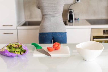 Mutfakta domates doğrayan bir kadın. Salata hazırlığı. Sağlıklı yaşam tarzı ve beslenme konsepti.