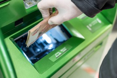 Erkekler, koronavirüs sırasında ATM 'ye beş bin banknot (para) yatırırlar. Salgın. 