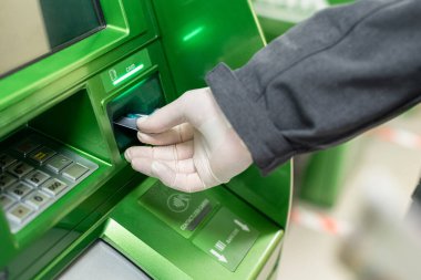 Erkekler, Coronavirus 'a karşı ATM' de kredi kartı kullandığını gösteren koruyucu lastik eldivenler veriyorlar. Salgın. 
