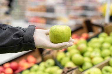Koruyucu lastik eldivenli bir kurye markette, süpermarkette online alışveriş için yeşil elma seçiyor. Bakteri ve virüsten korunma. Coronavirus. daha az güvenli teslimat