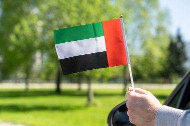 Açık araba camında Birleşik Arap Emirlikleri (BAE) bayrağı tutan adam. Kavram