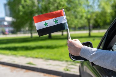 Açık arabanın camından Suriye bayrağı tutan adam. Kavram