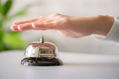 Gümüş çan çalan bir misafir. Kopya alanı olan resepsiyon masası. Otel servisi. Seçici odak