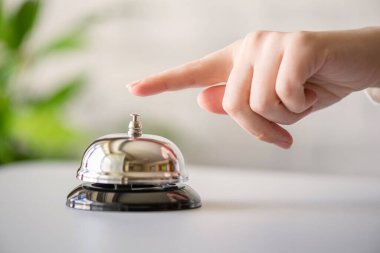 Gümüş çan çalan bir misafir. Kopya alanı olan resepsiyon masası. Otel servisi. Seçici odak