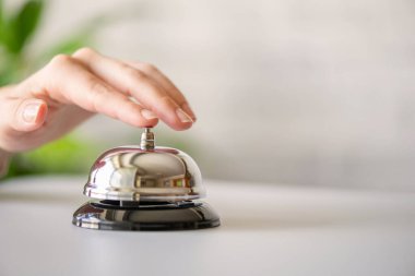 Gümüş çan çalan bir misafir. Kopya alanı olan resepsiyon masası. Otel servisi. Seçici odak