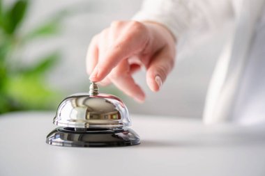 Gümüş çan çalan bir misafir. Kopya alanı olan resepsiyon masası. Otel servisi. Seçici odak