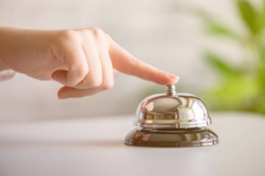 Gümüş çan çalan bir misafir. Kopya alanı olan resepsiyon masası. Otel servisi. Seçici odak