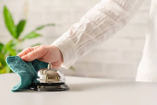 Hand of woman cleaning ringing bell on reception desk. disinfection spray, small towel. Protection from bacteria and virus. Keeping health of guests. Hotel service. Selective focus