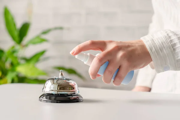 Hand of woman cleaning ringing bell on reception desk. disinfection spray, small towel. Protection from bacteria and virus. Keeping health of guests. Hotel service. Selective focus