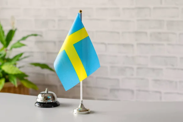 Silver vintage bell with national flag of Sweden on reception desk with copy space. Hotel service. Travel, tourism. Selective focus. Europe, Concept.