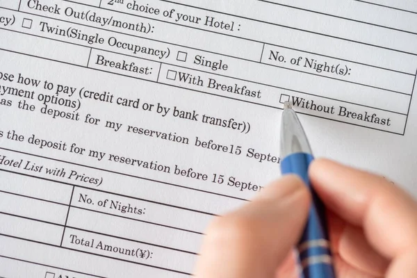 Woman filling hotel reservation form check mark choosing without breakfast in hotel service. Reception desk, registration. Close up. Selective focus.