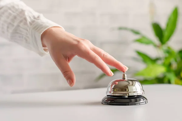 Hand of guest ringing in silver bell. reception desk with copy space. Hotel service. Selective focus