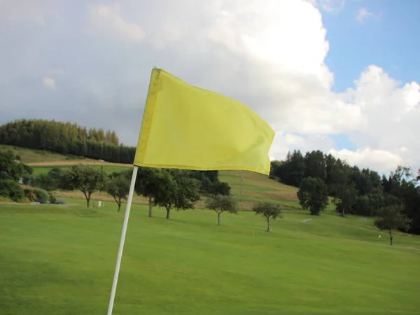 Żółtą flagę wietrznie na polu golfowym na górze — Zdjęcie stockowe