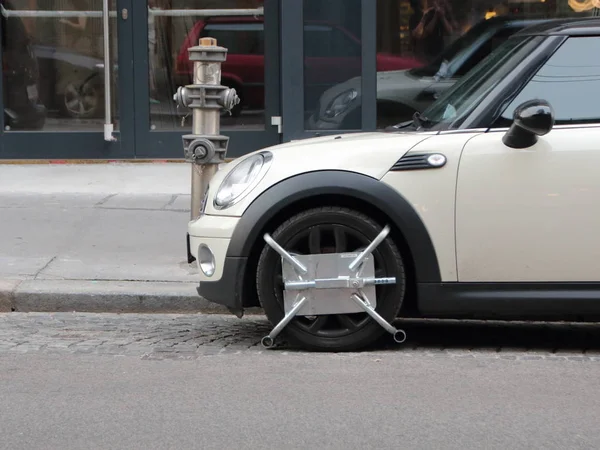 Petite voiture avec bloc de roue garée à la bouche d'incendie Photo De Stock