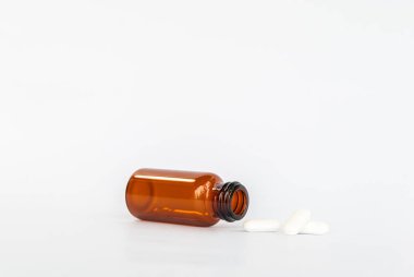 Boş ambalaj reçeteli kahverengi cam ilave ilaç beyaz arka planda izole beyaz haplar 