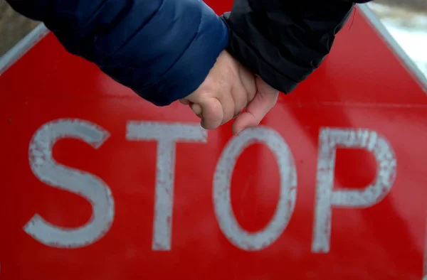 Eine Mutter hält die Hand ihres Sohnes, im Hintergrund: ein Stoppschild. — Stockfoto