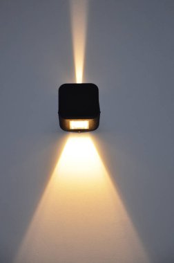 Küçük bir sokak lambası duvarı aydınlatıyor. Geniş ve dar ışık demetleri. Parlak