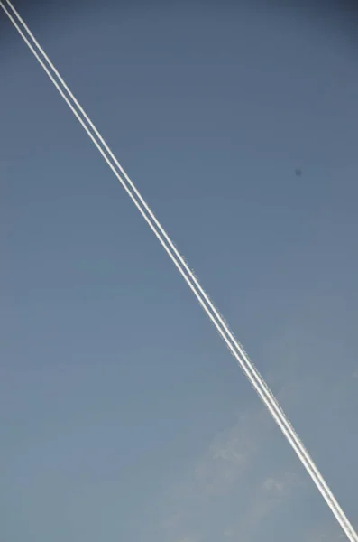 A diagonal line of smoke against the blue sky. A trace of an airplane