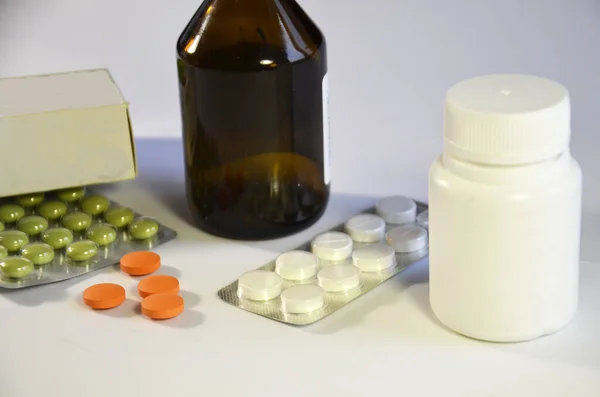 药物站在白色的背景上 距离很近 一只深色玻璃瓶 一包药丸 橙色药丸放在桌上 药箱各种各样的药物 传统医药 — 图库照片