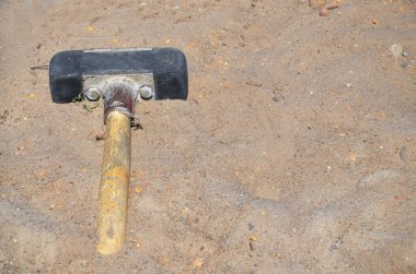 Balyoz kumun üzerinde yatıyor. Kumlu yüzeyde büyük bir çekiç yatar. Kapatın. Konsept: İnşaat, inşaat konusu.