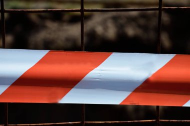 Kırmızı ve beyaz uyarı bandı, yakın plan. Geçmişi. Kavram: uyarı, yasak geçiş, tehlike bölgesi, çitli bölge