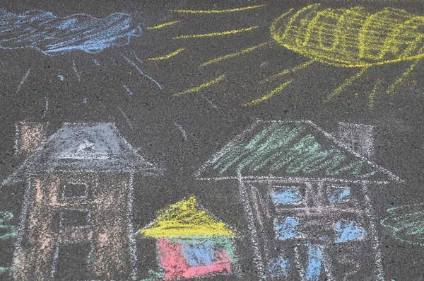 Children\'s multi-colored drawing on the road. The house, the sun, a cloud drawn by a child with crayons on the pavement. Colorful, beautiful image.