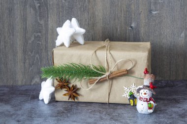 Christmas gift with white stars, with a cinnamon stick and a sprig of Christmas tree and snowmen figurines