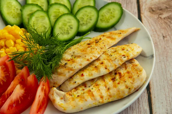 Salatalıklı ızgara tavuk, domates, mısır ve bitkilerle.