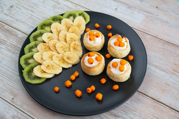 Cheesecakes with sour cream sauce, bananas and sea buckthorn berries