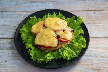 Peynirin altında mantarlı, fasulyeli ve domatesli tavuklu fileto salata yaprağı.