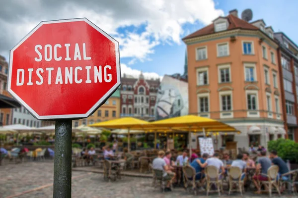 Social Distancing concept. Sign with social distancing work with cafe with people blur background. Preventive measures for containing corona virus, coronavirus outbreak. Keep the 2 meter distance.