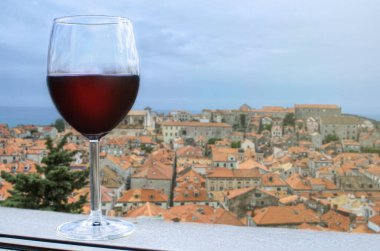 Hırvatistan 'daki tarihi Akdeniz kulesinin sazlık çatıları manzaralı bir bardak kırmızı şarap