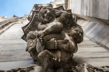 Milan Katedrali 'nin ön cephesinde heykel. Gotik mimari. İki bebek melek. İtalya 'daki Milan Duomo Katedrali' nin dış cephesinde bir heykelin yakın çekimi. Aşağıdan görüntüle.