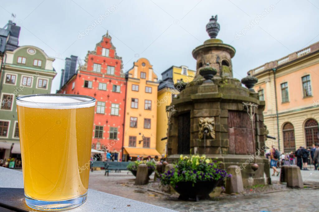 Glass of light beer against view of Stockholm city center on Gamla stan, Sweden. Stortorget in Old City, the Oldest Square in Stockholm