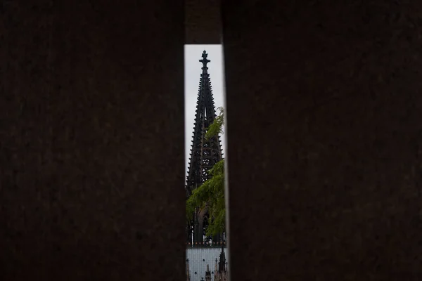 Köln, Almanya - 10 Mart 2019 'da ünlü Köln Kubbesi' ni duvardaki bir yarıktan izleyin. Sadece bir kule görünüyor, bir görüntünün her iki tarafında da karanlık..