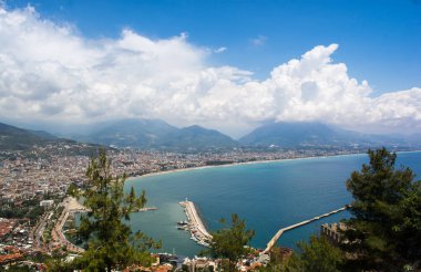 Ufukta bulutlar olan deniz yüzeyi ve arka planda dağlar olan son sınır kasabası.