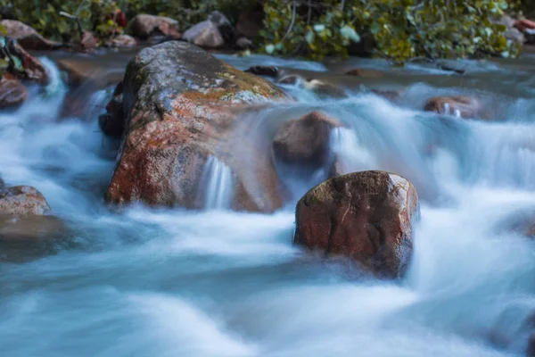 Scena natury szorstka, szybko płynąca rzeka uderzająca w kamienie, tworząc mini wodospady. — Zdjęcie stockowe