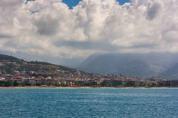 Denize yakın bir tatil. Denizde çok güzel bir gün, güneşli bir hava, dağlar ve arka planda bulanık bir sahil kasabası..